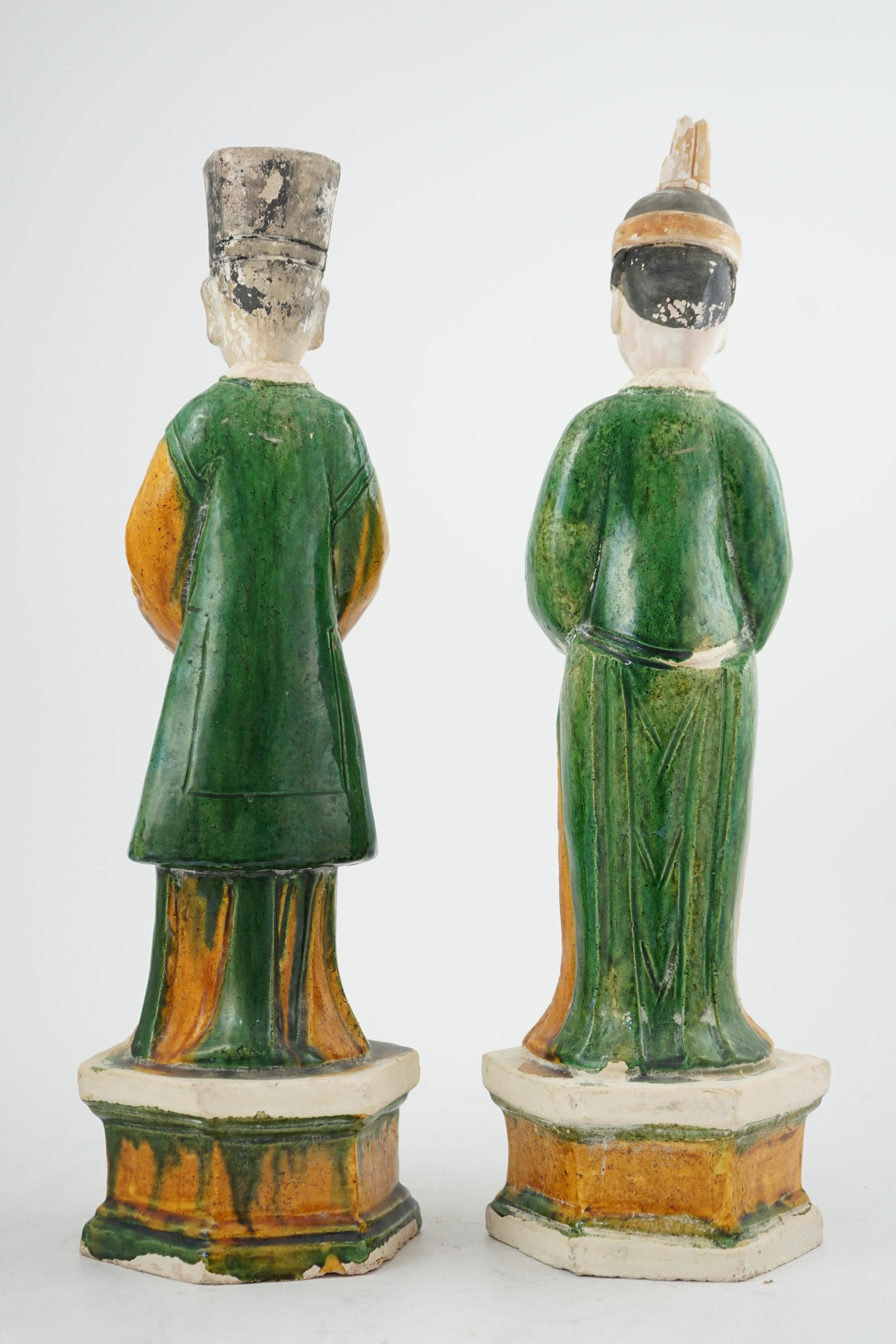 Two tall Chinese sancai figures of attendants, Ming dynasty, the male figure holding a dish and the female figure a box, each standing on a hexagonal base, largest 47cm high. Condition - some wear to face